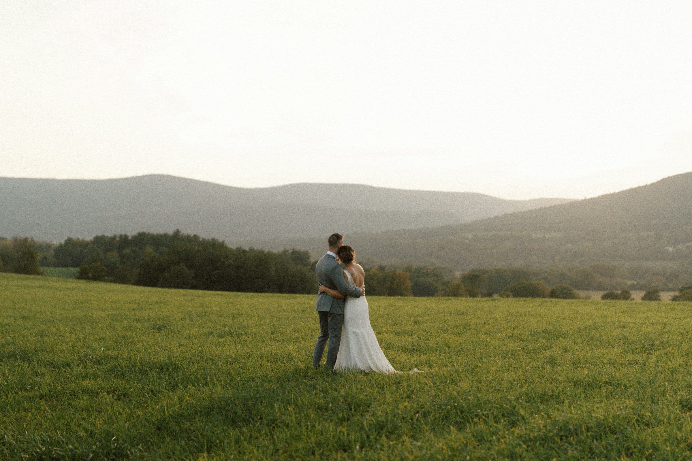 Amara and Daniel embracing in a valley field at golden hour